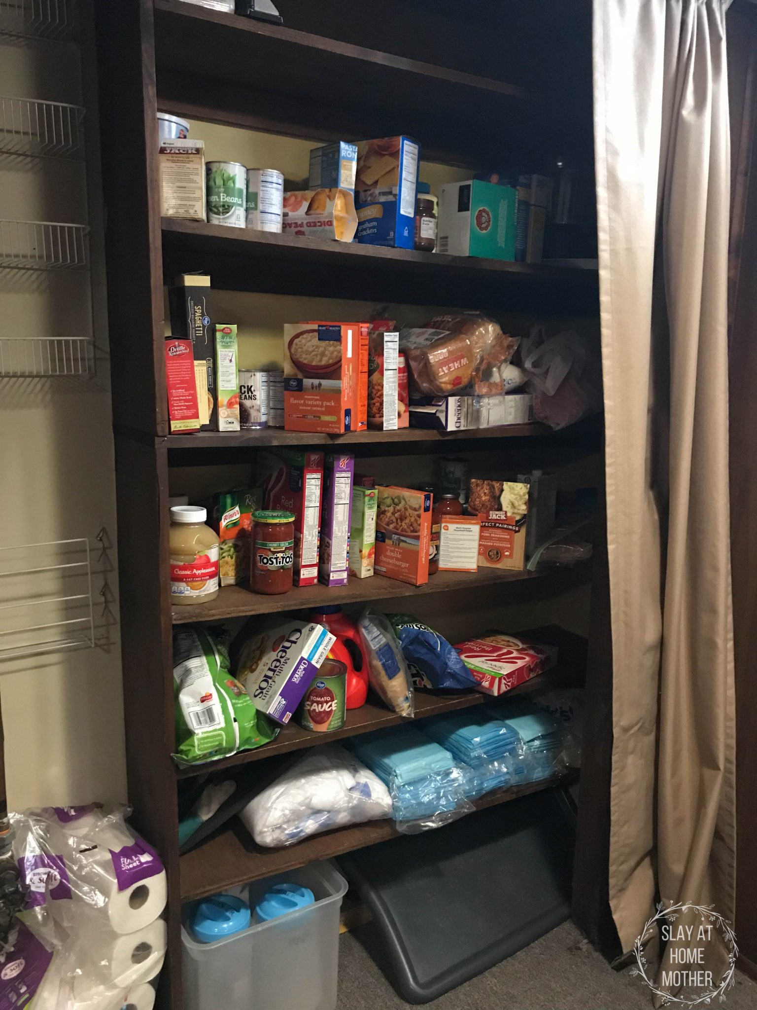 A side view of my messy pantry with brown shelves, tan curtains, and yellow walls