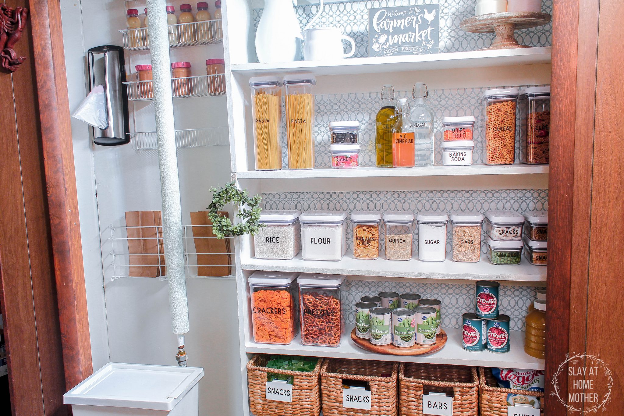 My finished pantry with white walls, contact paper wallpaper, and dry goods organized in labeled bins and baskets