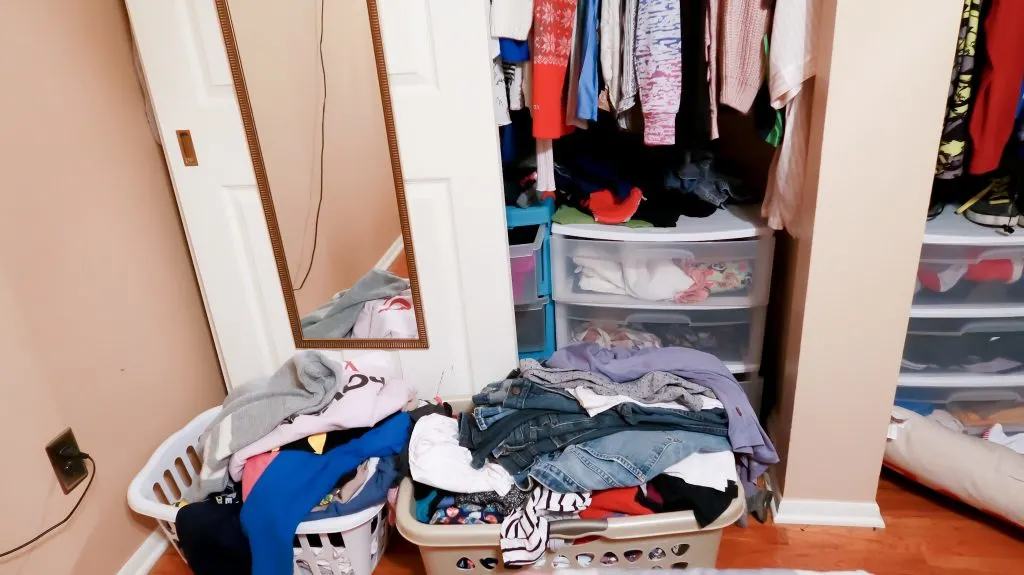 before shot of bedroom closet, including two filled baskets outside closet doors filled with clothing.