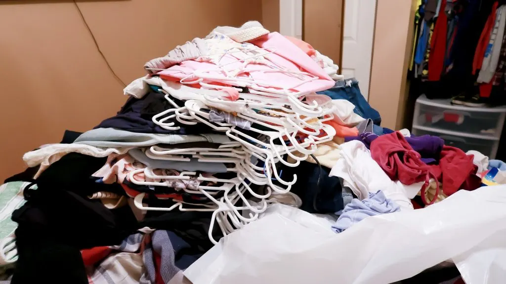 stack of clothes taken from master bedroom closet during KonMari decluttering phase