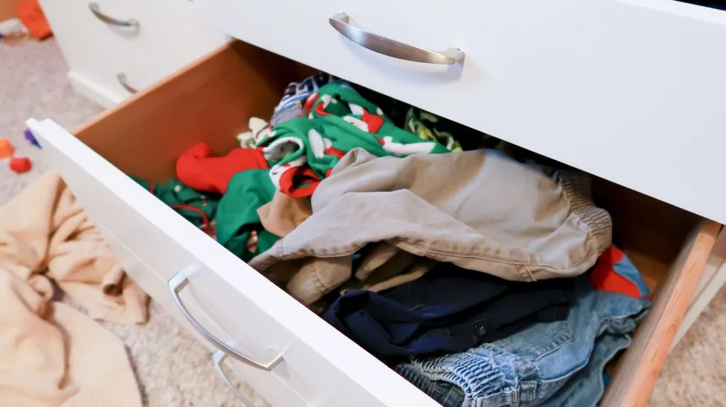 pants drawer with clothes shoved in, disorganized.