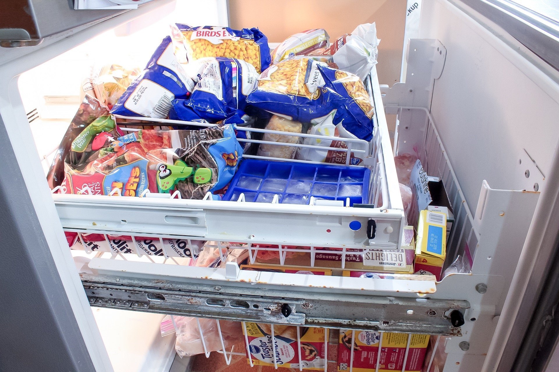 My freezer before organizing - the drawers are overflowing with food and completely disorganized.