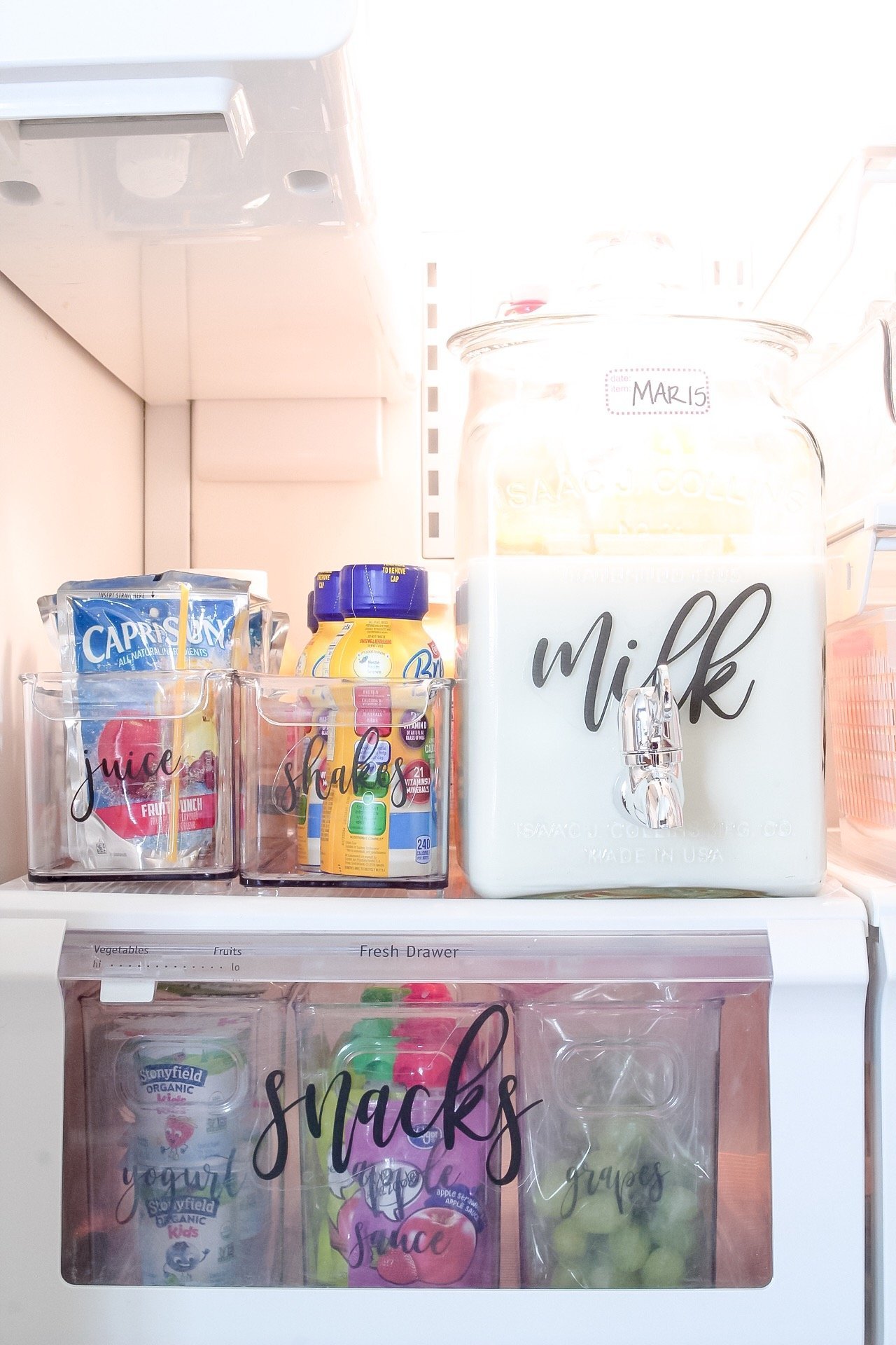 A closeup of our drinks in our fridge - including our milk in a beverage dispenser, and our kids' shakes and juices in long containers