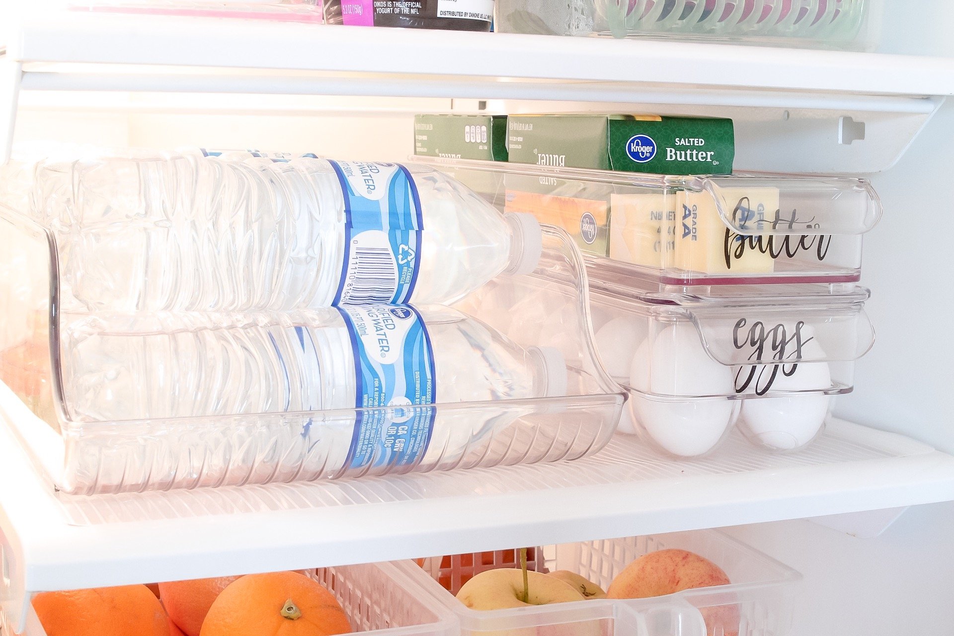 Containers holding waters, butter, and eggs in our organized fridge