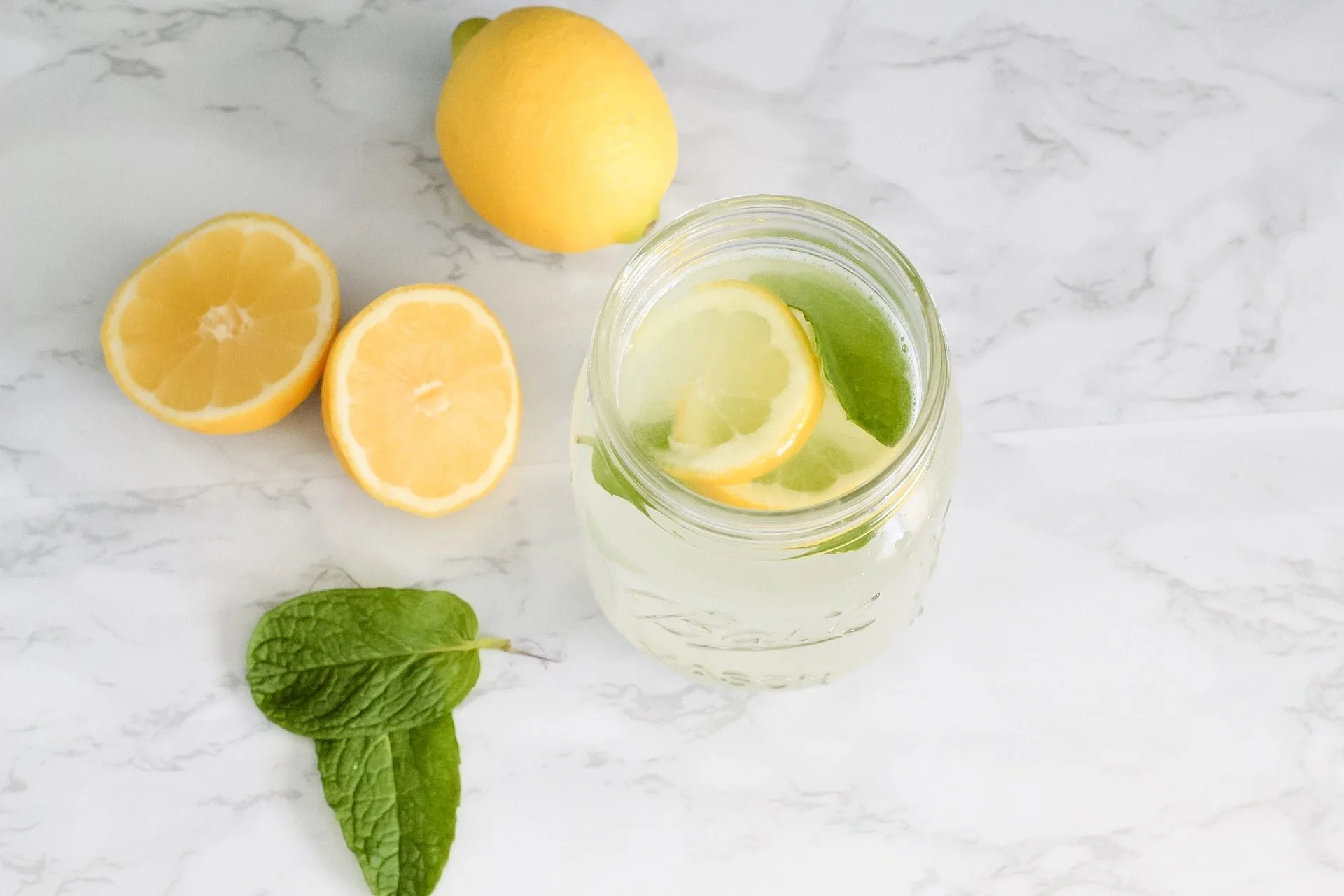 refreshing mint lemonade in a mason jar with fresh lemon slices and sprigs of mint