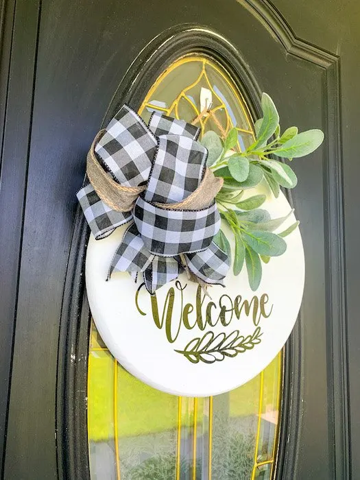 finished diy round sign on front door with bow and greenery