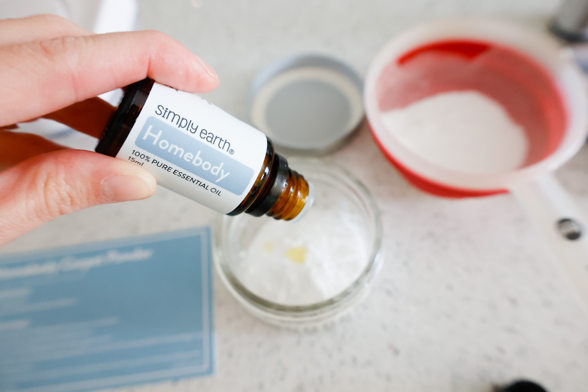 dropping essential oils on top of baking soda in jar 