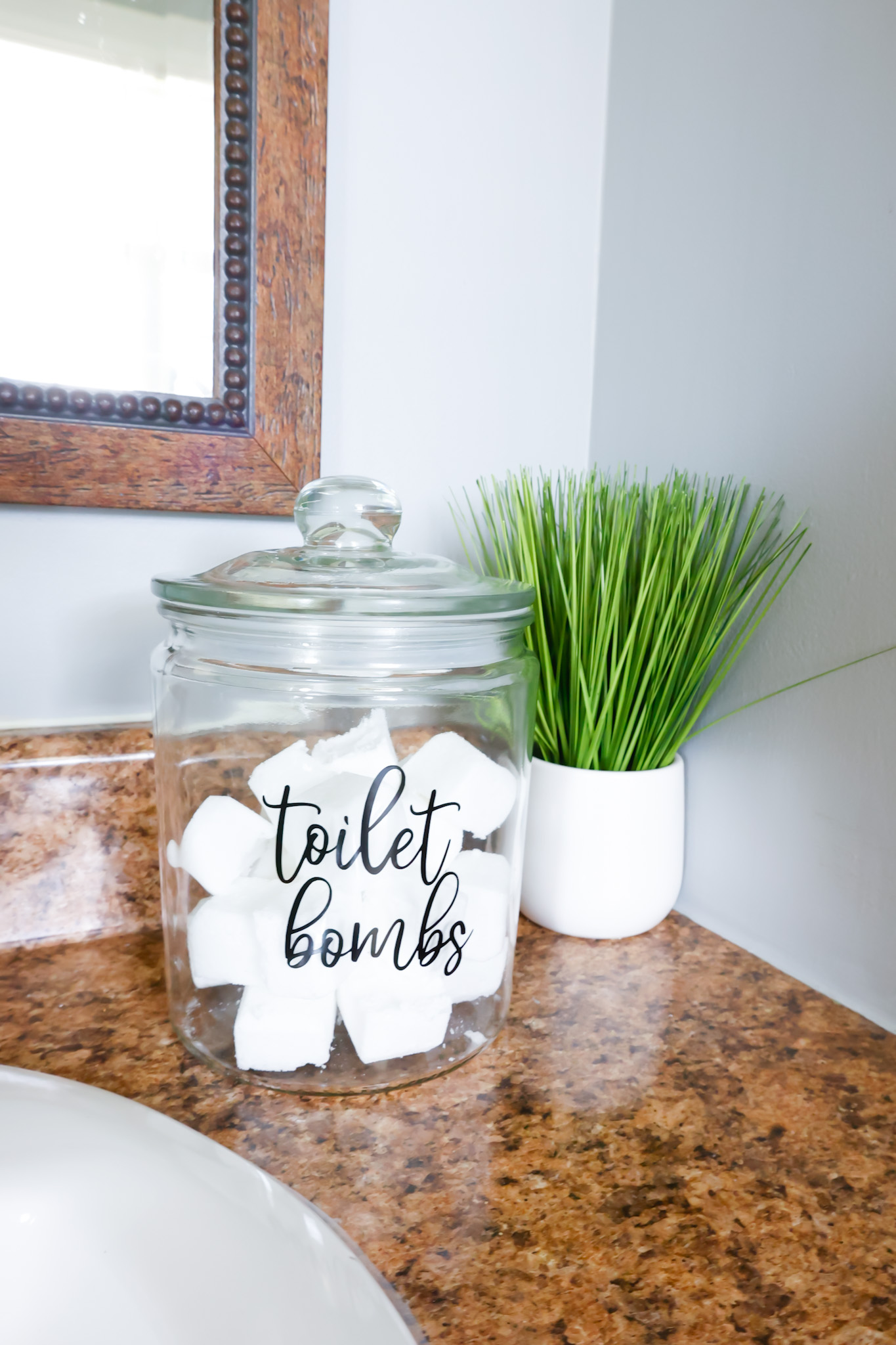 finished toilet bowl cleaning bombs in apothecary jar on bathroom counter