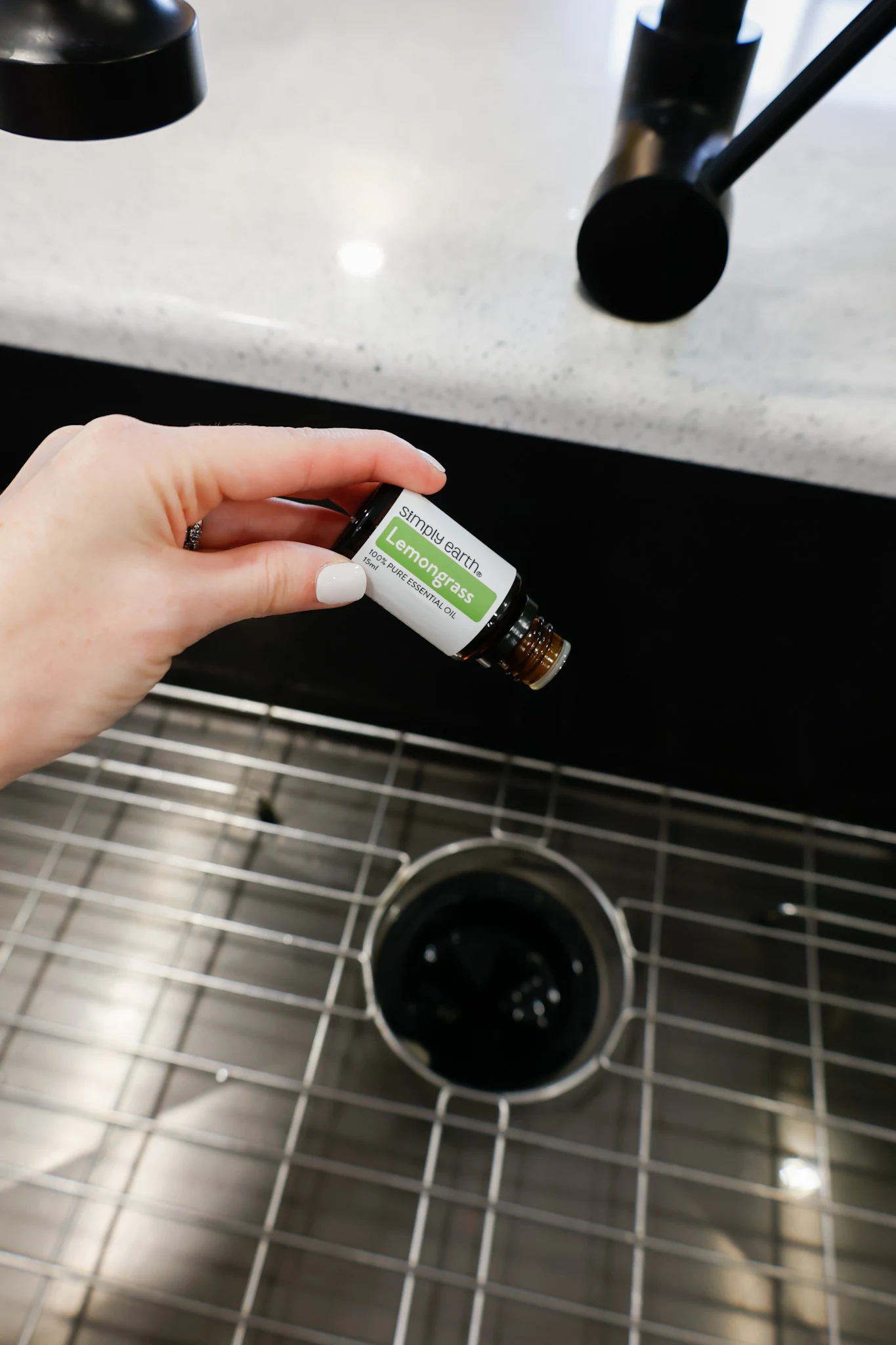 pouring lemongrass essential oil into garbage disposal