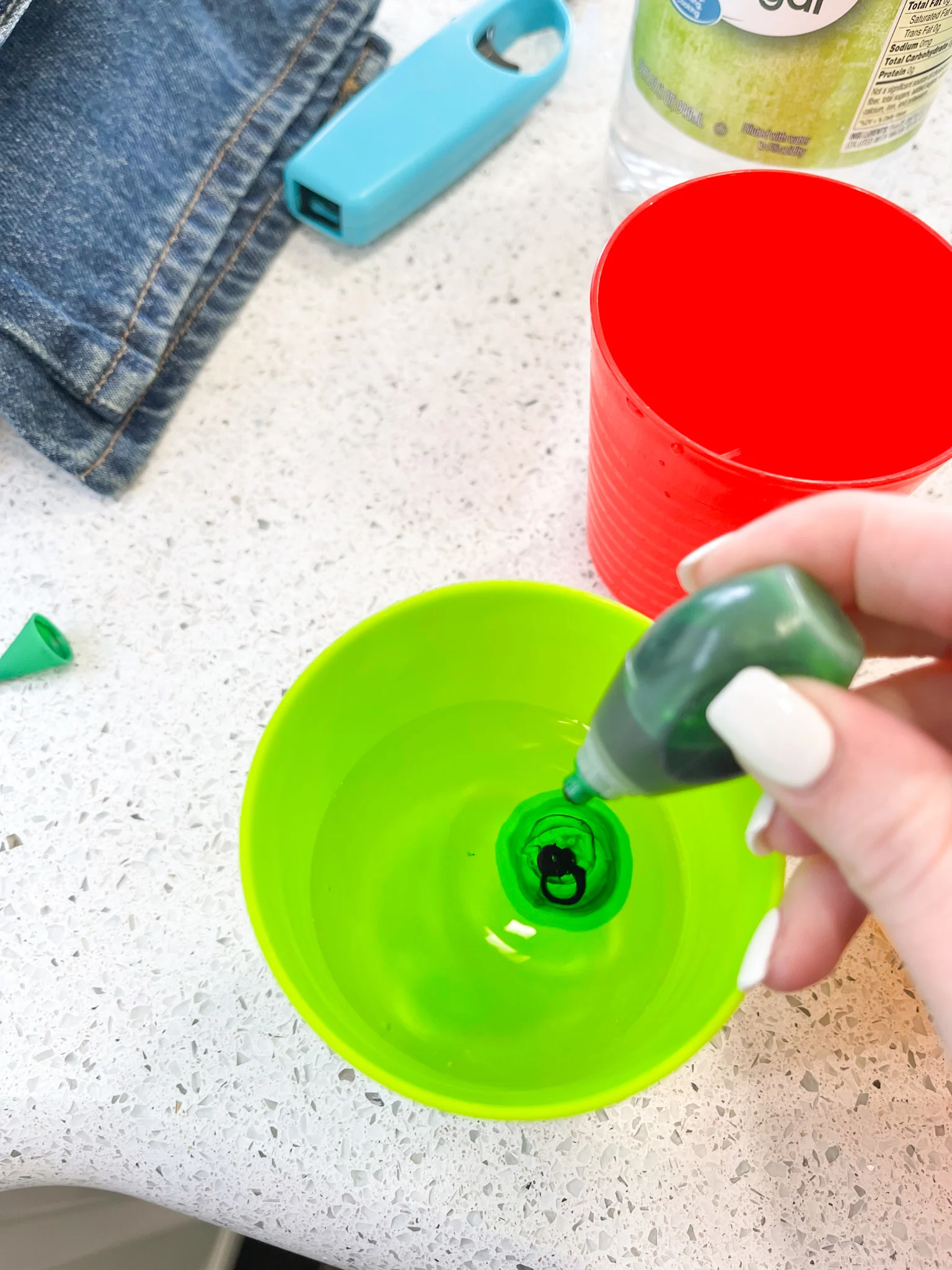 adding food coloring to cup to dye easter eggs