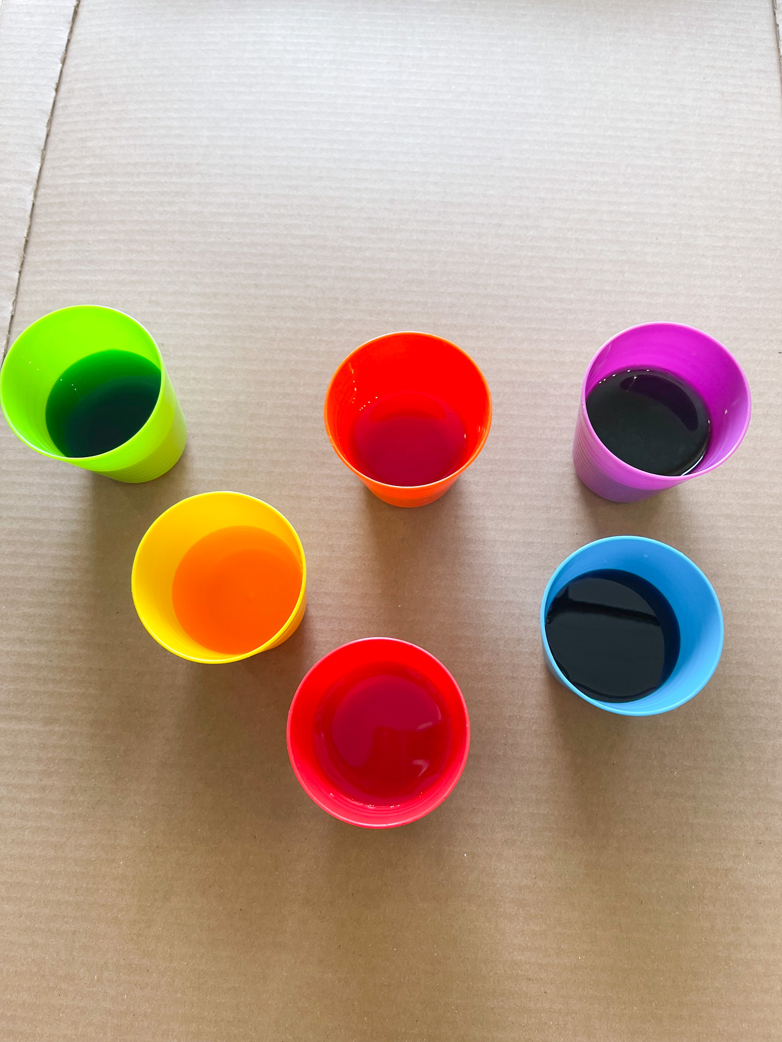 6 cups of food coloring dye on cardboard