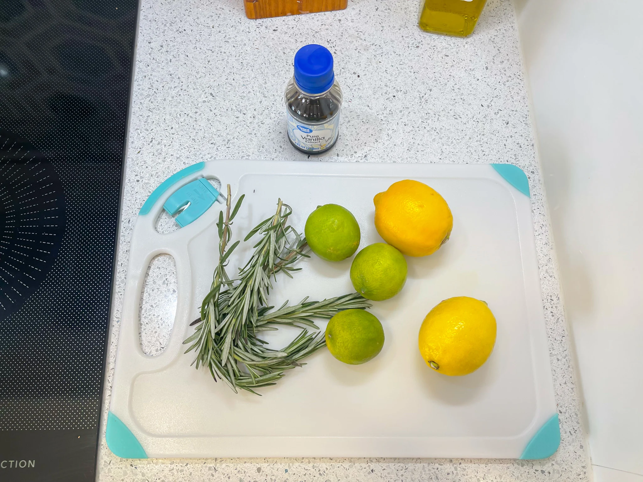 lemons limes reosemary and vanilla extract on a cutting board 