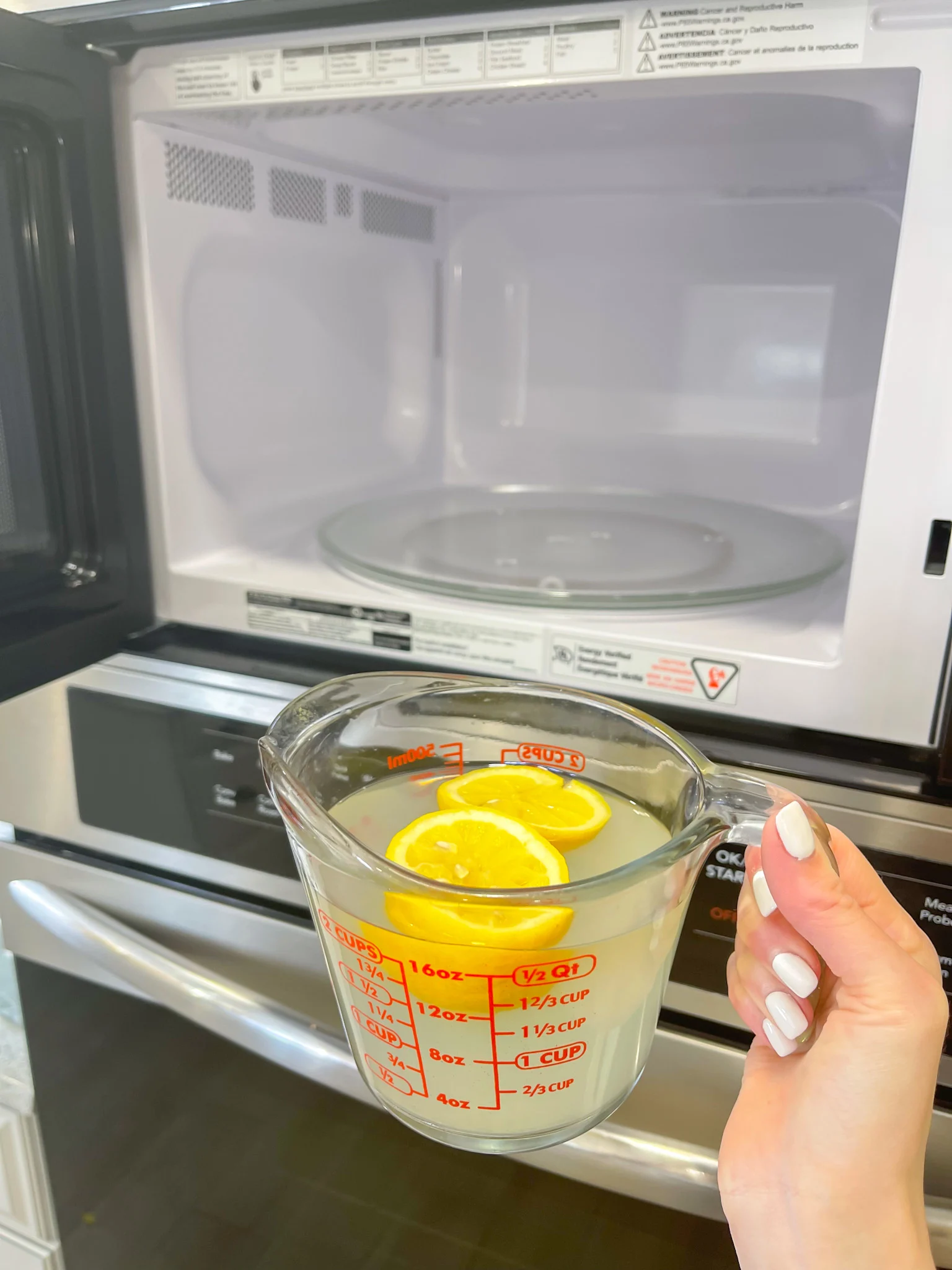 used lemons in measuring cup in front of microwave 