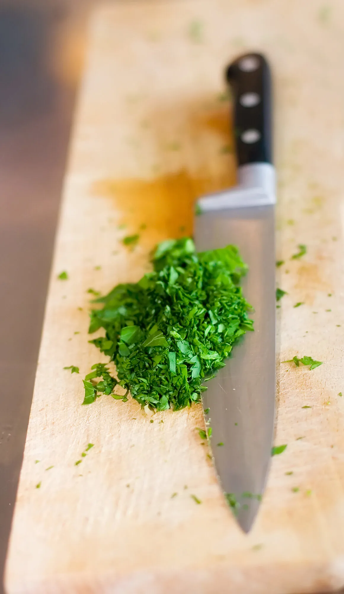 knife cutting herbs on cutting board